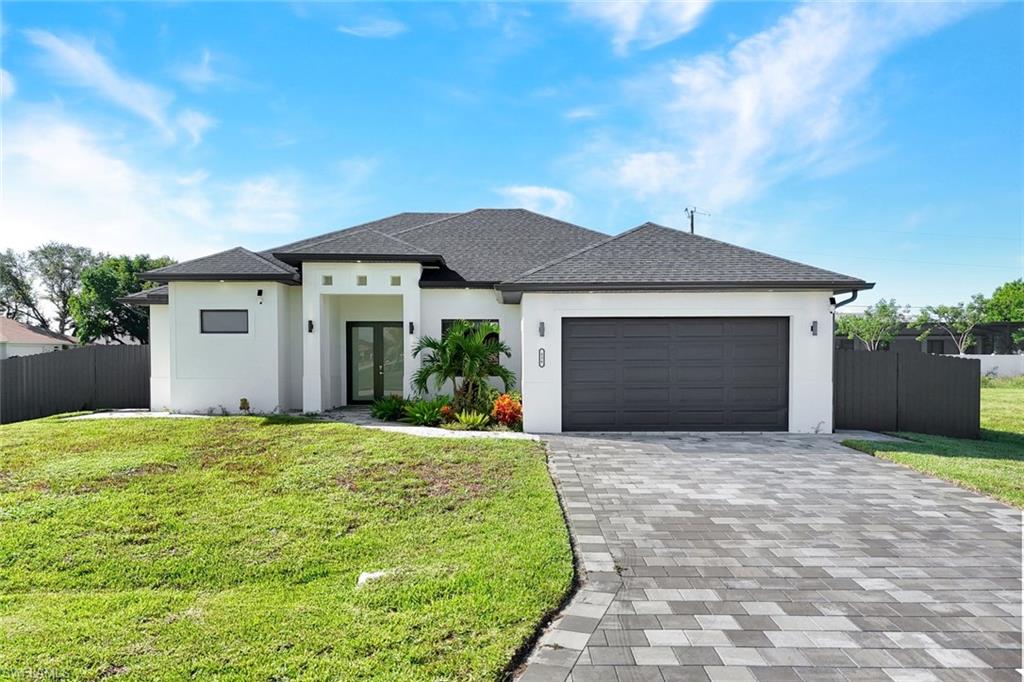 Modern house with stucco siding, decorative driveway, a shingled roof, and an attached garage