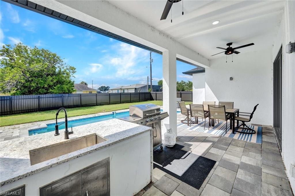 Fenced backyard with outdoor dining space, exterior kitchen, a patio, and a ceiling fan
