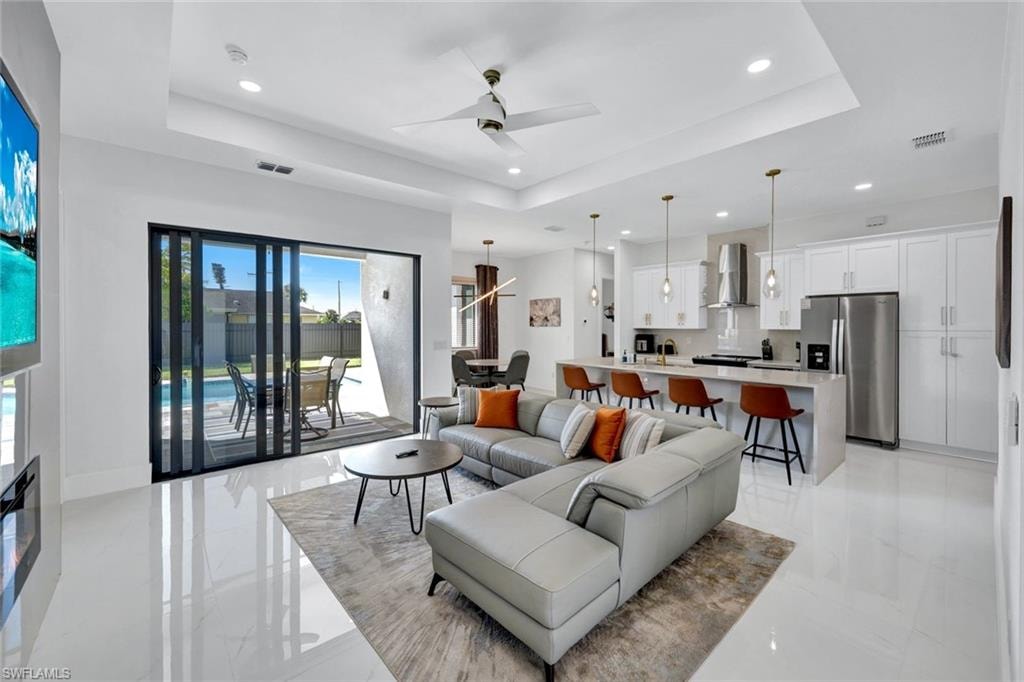 Living area with a raised ceiling, a ceiling fan, and recessed lighting