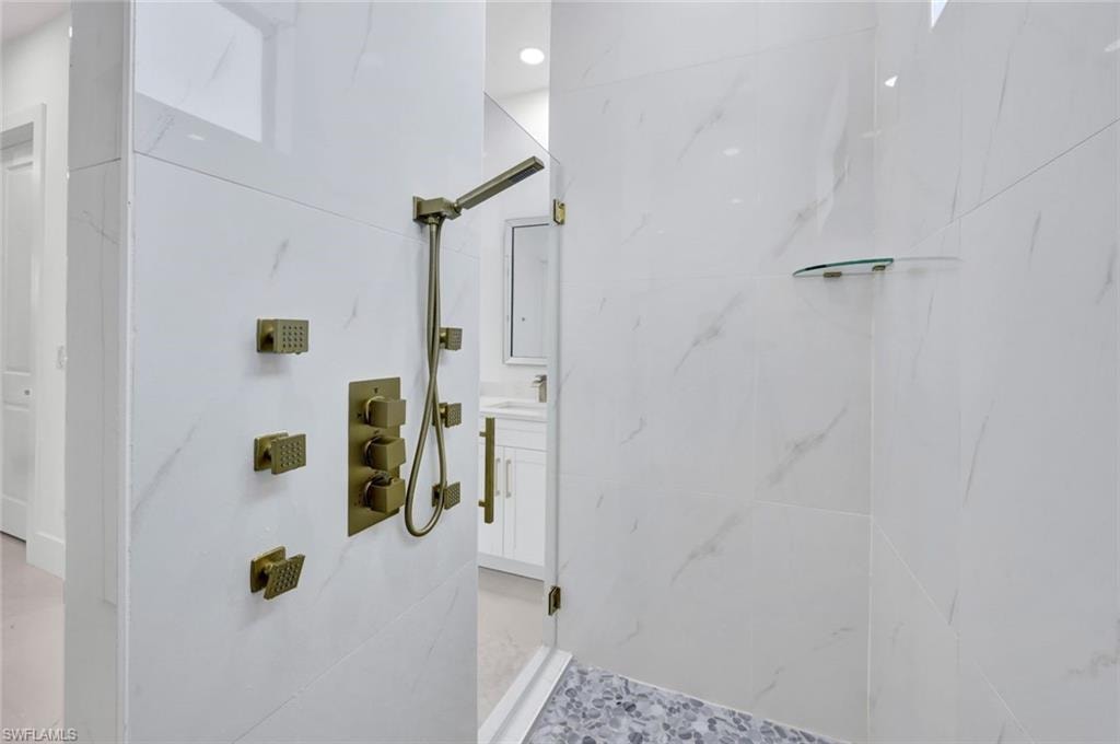 Bathroom featuring a marble finish shower, multiple shower heads and vanity
