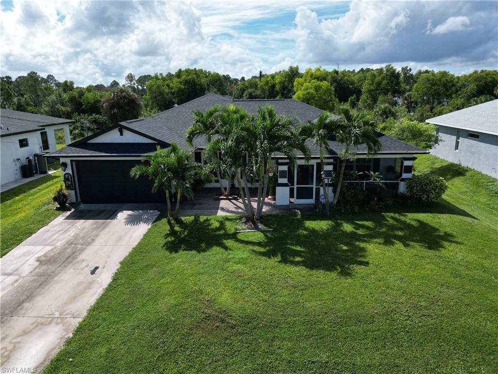 Ranch-style home featuring concrete driveway, a front yard, an attached garage, and roof with shingles