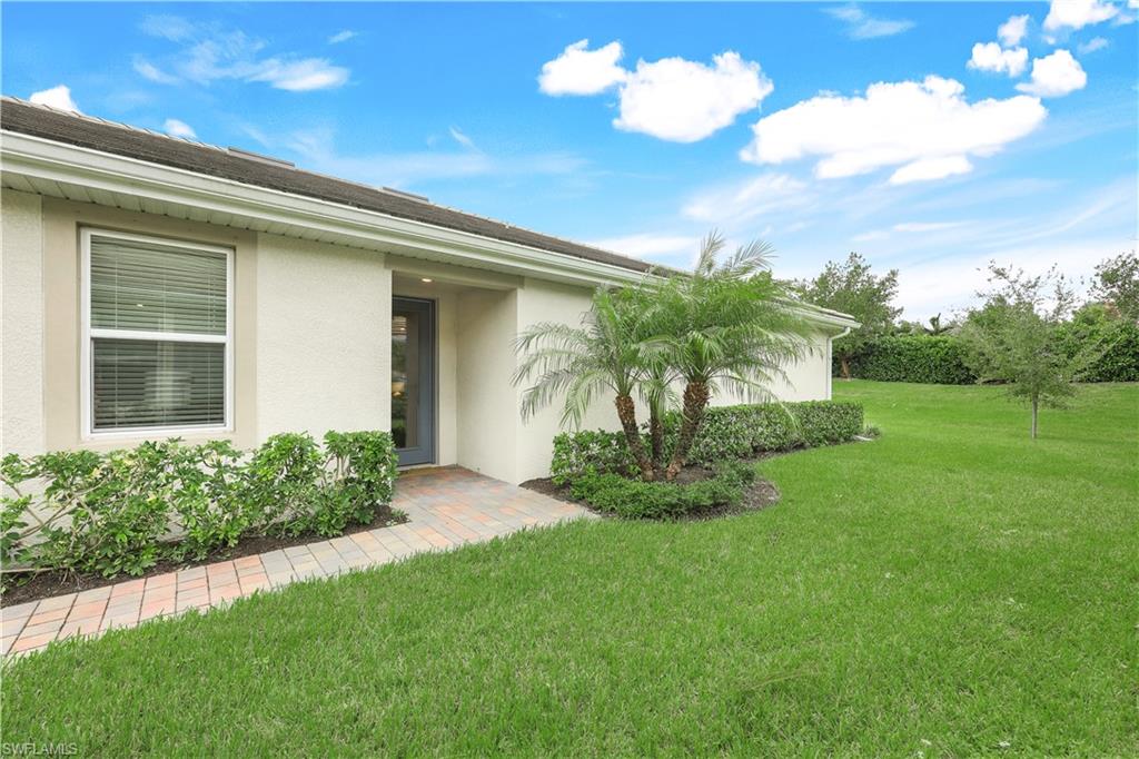 View of exterior entry featuring stucco siding and a lawn