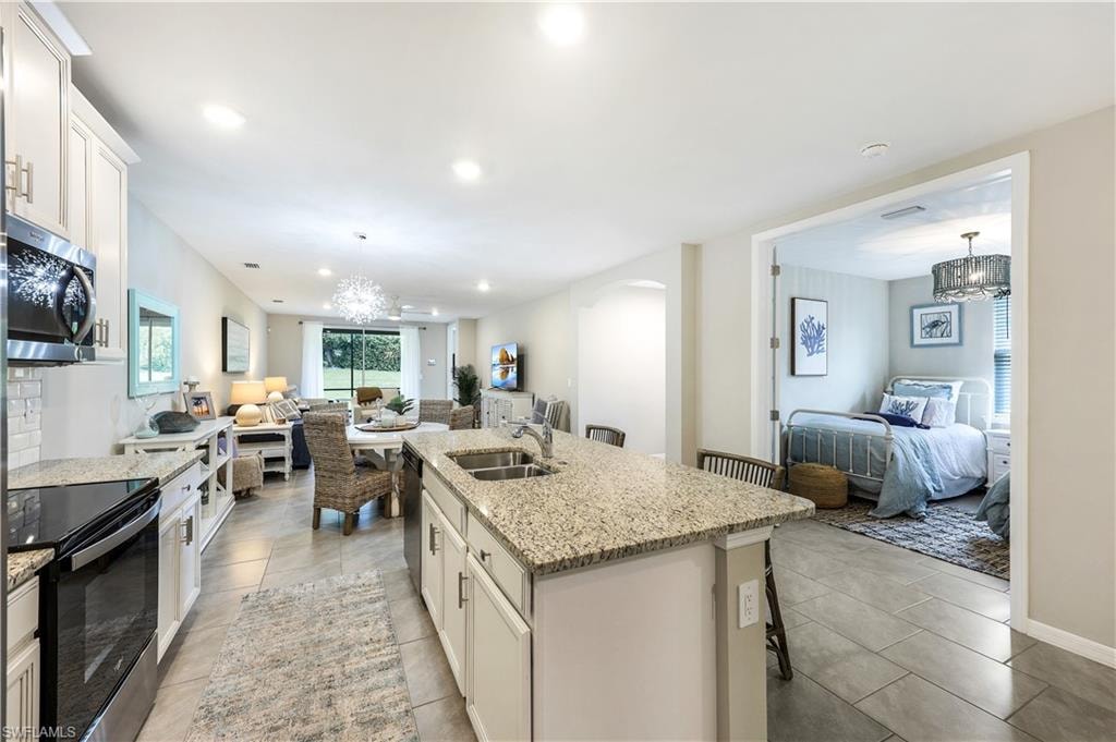 Kitchen with open floor plan, white cabinetry, a chandelier, appliances with stainless steel finishes, and recessed lighting