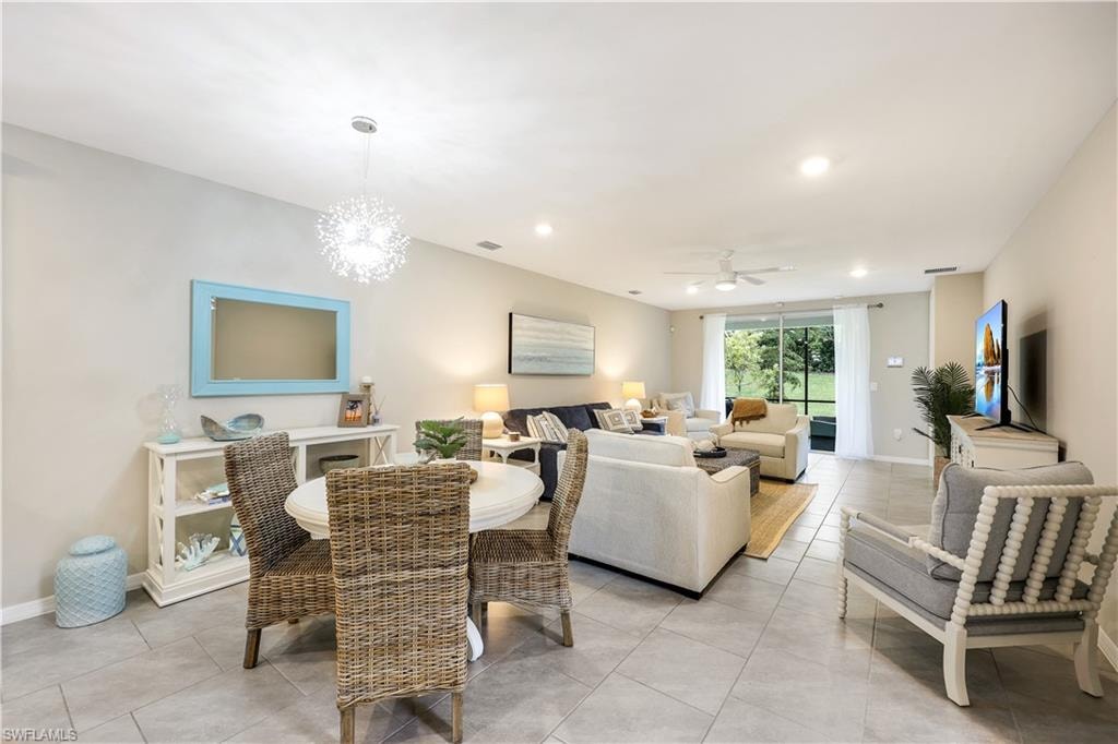 Dining space featuring light tile patterned floors, recessed lighting, ceiling fan, and a chandelier