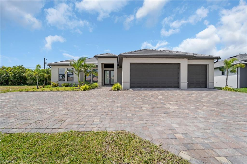 Prairie-style home featuring a garage, decorative driveway, and stucco siding