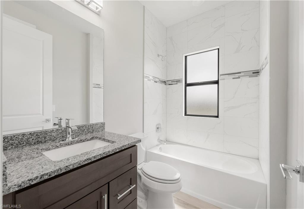 Bathroom featuring toilet, vanity, and shower / bathing tub combination