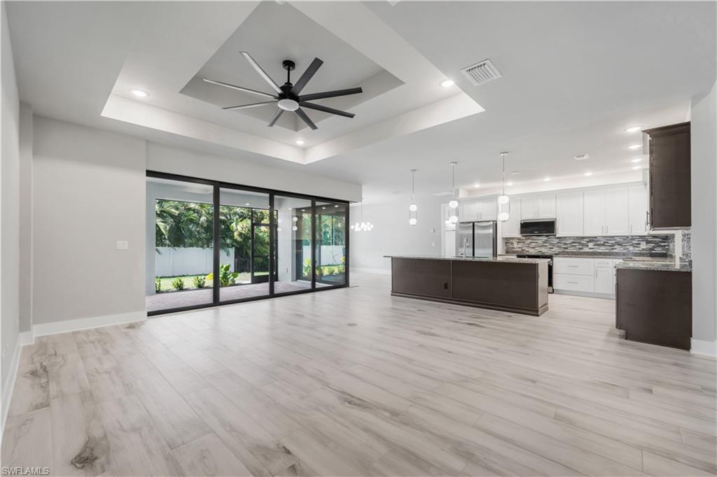 Unfurnished living room featuring recessed lighting, a raised ceiling, light wood-style floors, visible vents, and ceiling fan