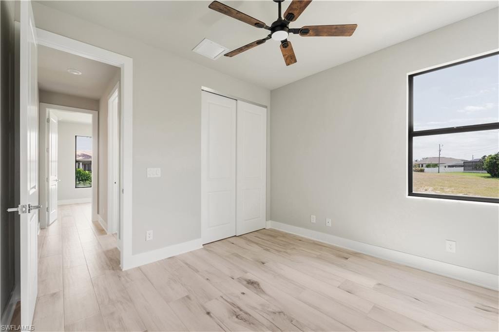 Unfurnished bedroom with a closet, light wood finished floors, baseboards, and a ceiling fan