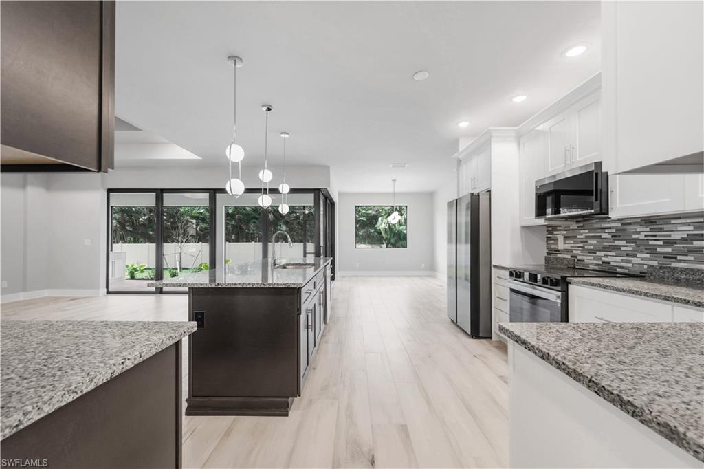 Kitchen with appliances with stainless steel finishes, a sink, decorative backsplash, baseboards, and plenty of natural light