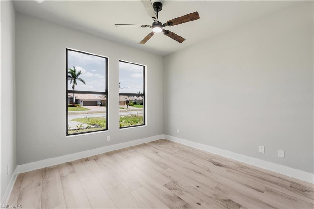 Unfurnished room featuring baseboards, a ceiling fan, and light wood-style floors