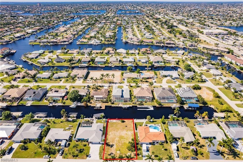 Aerial perspective of suburban area with a nearby body of water and property boundaries highlighted