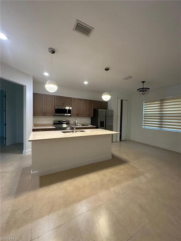 Kitchen featuring decorative light fixtures, a center island with sink, stainless steel appliances, recessed lighting, and a chandelier