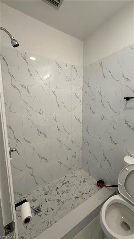 Full bath with a marble finish shower and toilet