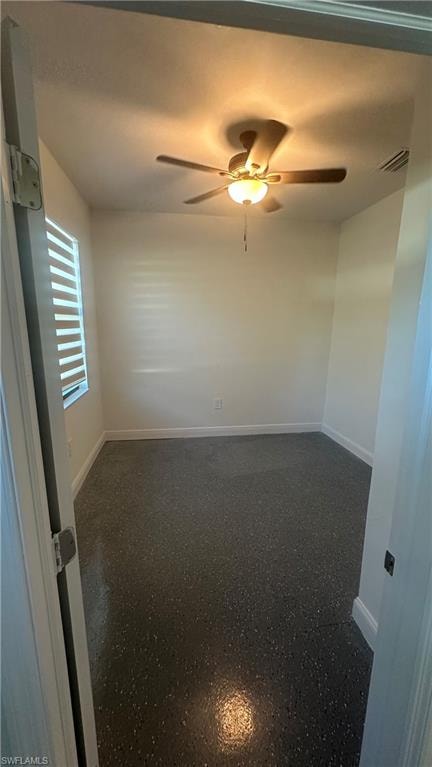 Unfurnished room featuring light speckled floor and a ceiling fan