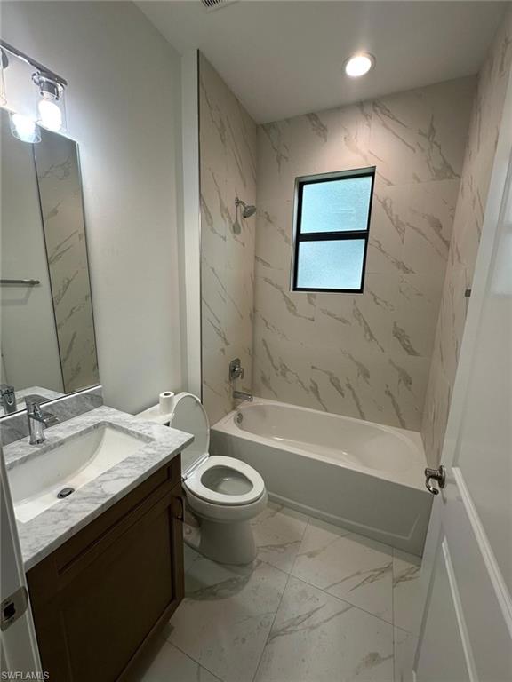 Bathroom featuring shower / bathtub combination, vanity, and light marble finish flooring
