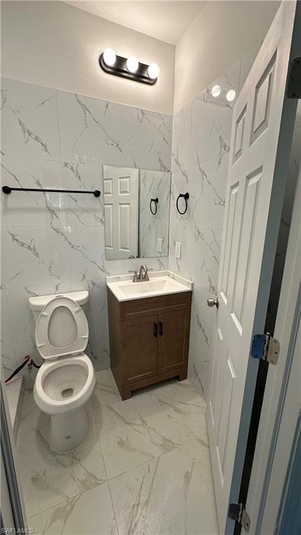 Bathroom featuring tile walls, vanity, and light marble finish floors