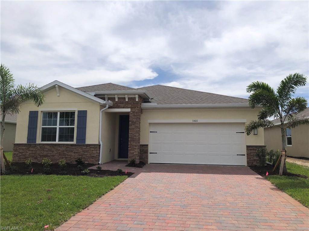 View of front facade with a front yard, decorative driveway, stucco siding, and an attached garage