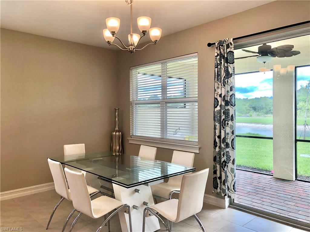 Kitchen featuring stainless steel appliances, backsplash, light stone counters, white cabinets, and an island with sink