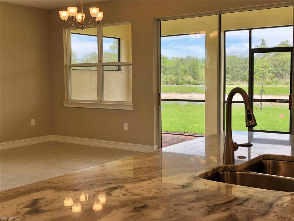 Kitchen featuring black appliances, a kitchen breakfast bar, white cabinets, light stone countertops, and recessed lighting