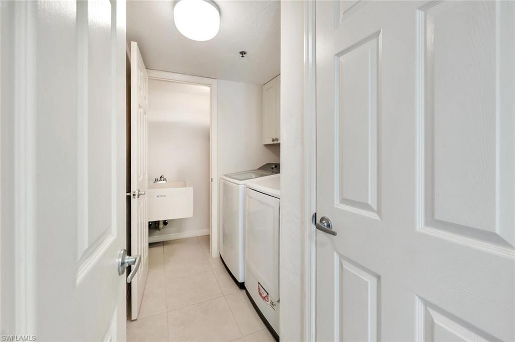 Washroom featuring light tile patterned floors, cabinet space, and washer and clothes dryer