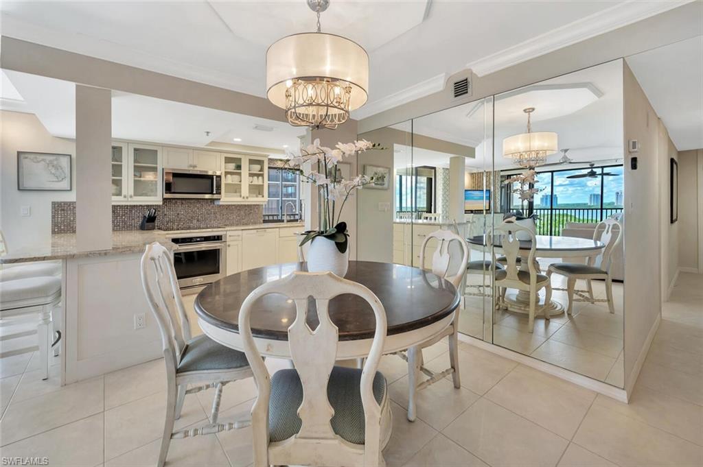 Dining space with ornamental molding, light tile patterned floors, and a chandelier