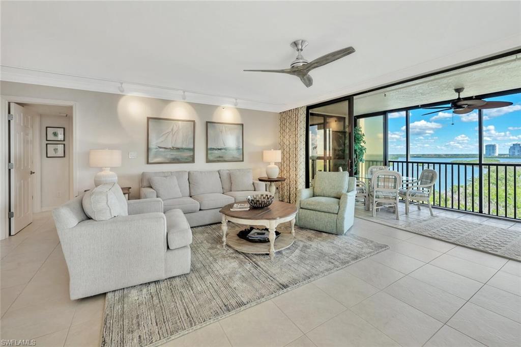 Living room featuring a water view, floor to ceiling windows, tile patterned flooring, ceiling fan, and track lighting