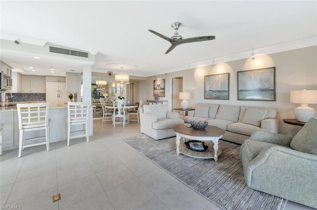 Living room with a ceiling fan, light tile patterned floors, track lighting, and a chandelier