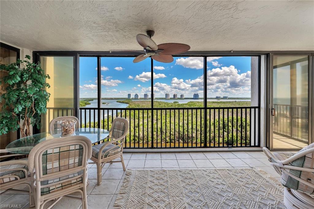 Sunroom with a wall of windows, a textured ceiling, a water view, and tile patterned flooring
