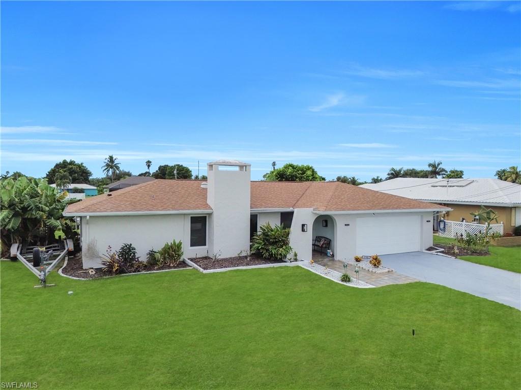 Single story home with driveway, a front yard, stucco siding, a garage, and a chimney