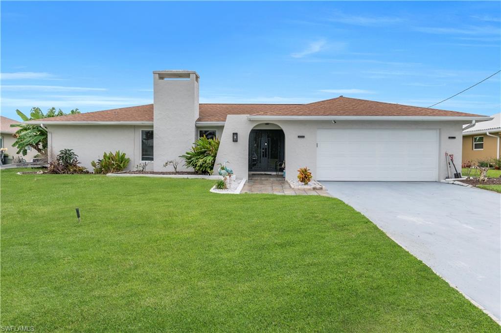 View of front of property with stucco siding, a front yard, concrete driveway, and an attached garage