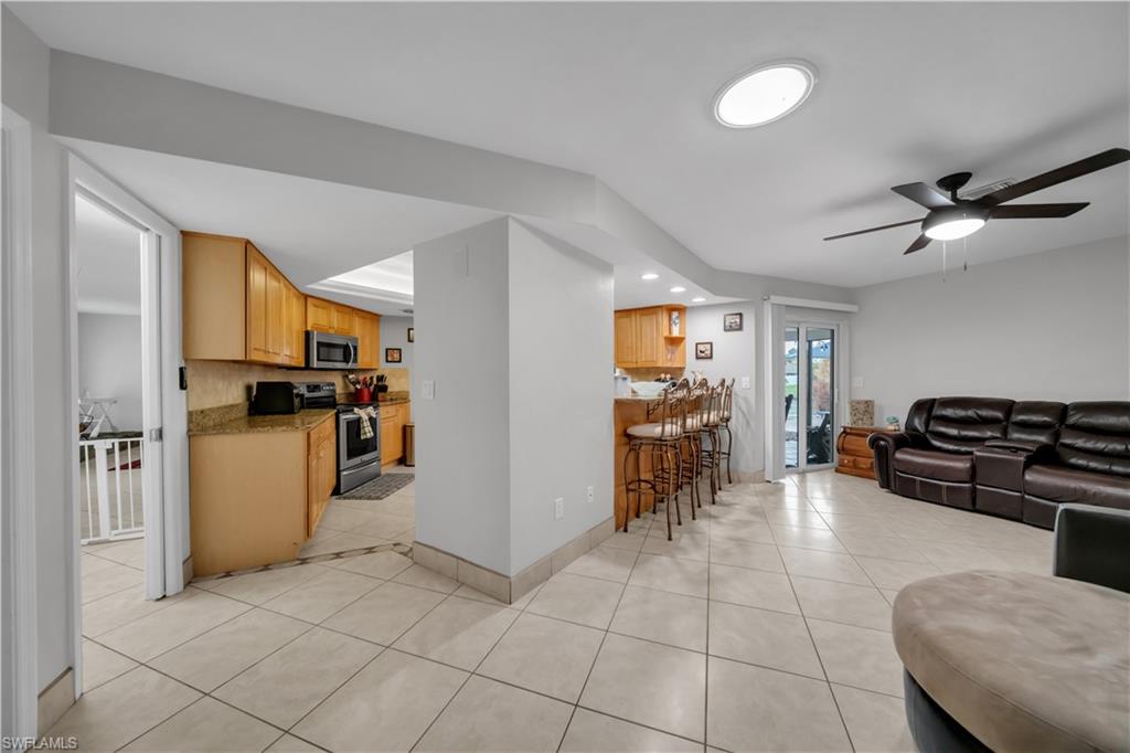 Living area with light tile patterned flooring, ceiling fan, and recessed lighting
