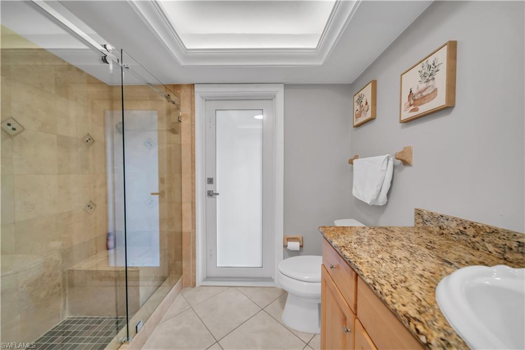 Full bath featuring vanity, light tile patterned floors, and a shower stall