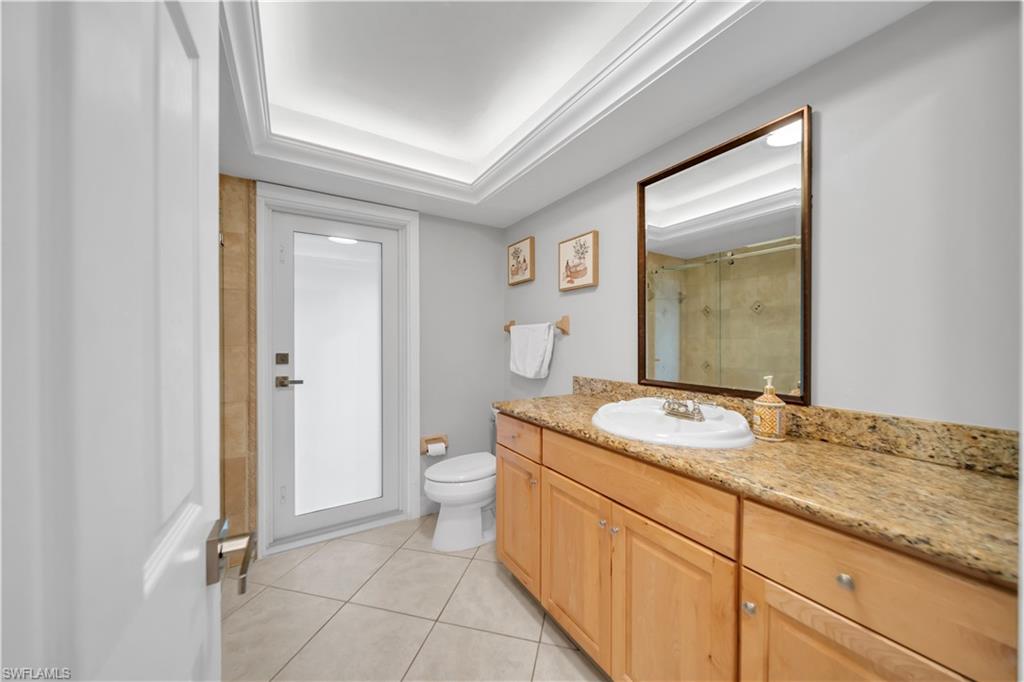 Full bath featuring vanity, light tile patterned floors, a shower stall, and a raised ceiling