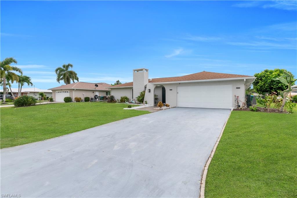 Ranch-style home featuring concrete driveway, a front yard, an attached garage, stucco siding, and a chimney