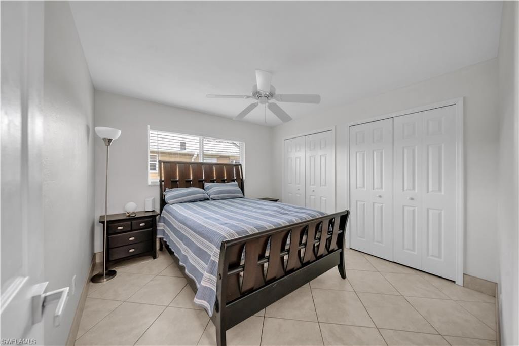 Bedroom with light tile patterned floors, two closets, and a ceiling fan