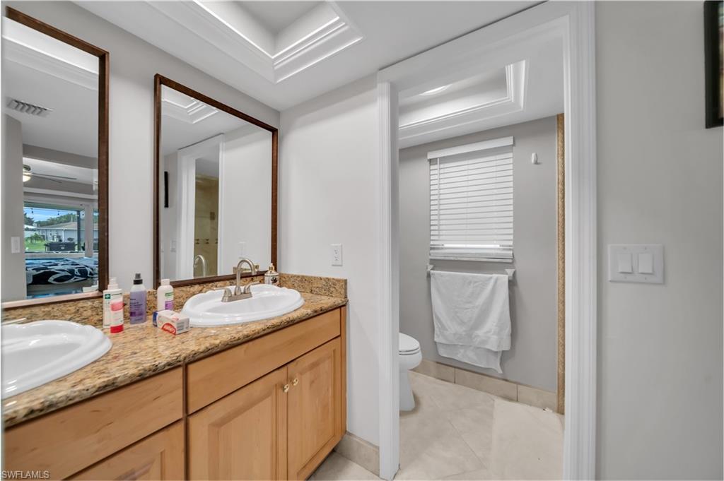 Bathroom featuring double vanity, ceiling fan, and light tile patterned floors