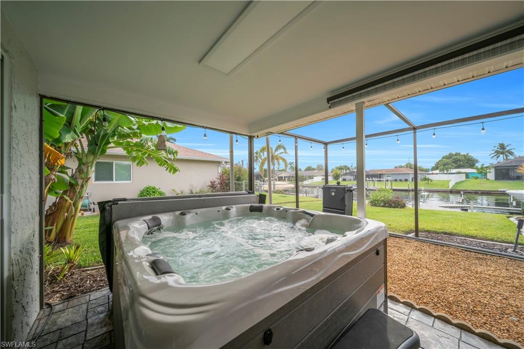 Sunroom featuring a jacuzzi, a residential view, and a water view
