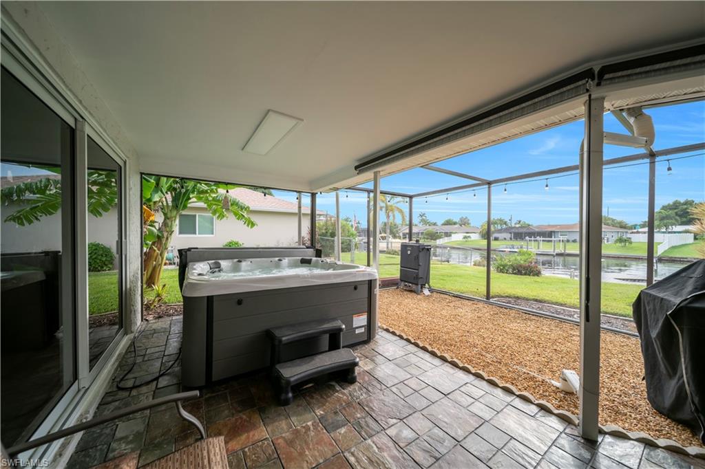 Sunroom featuring plenty of natural light, a jacuzzi, a residential view, and a water view