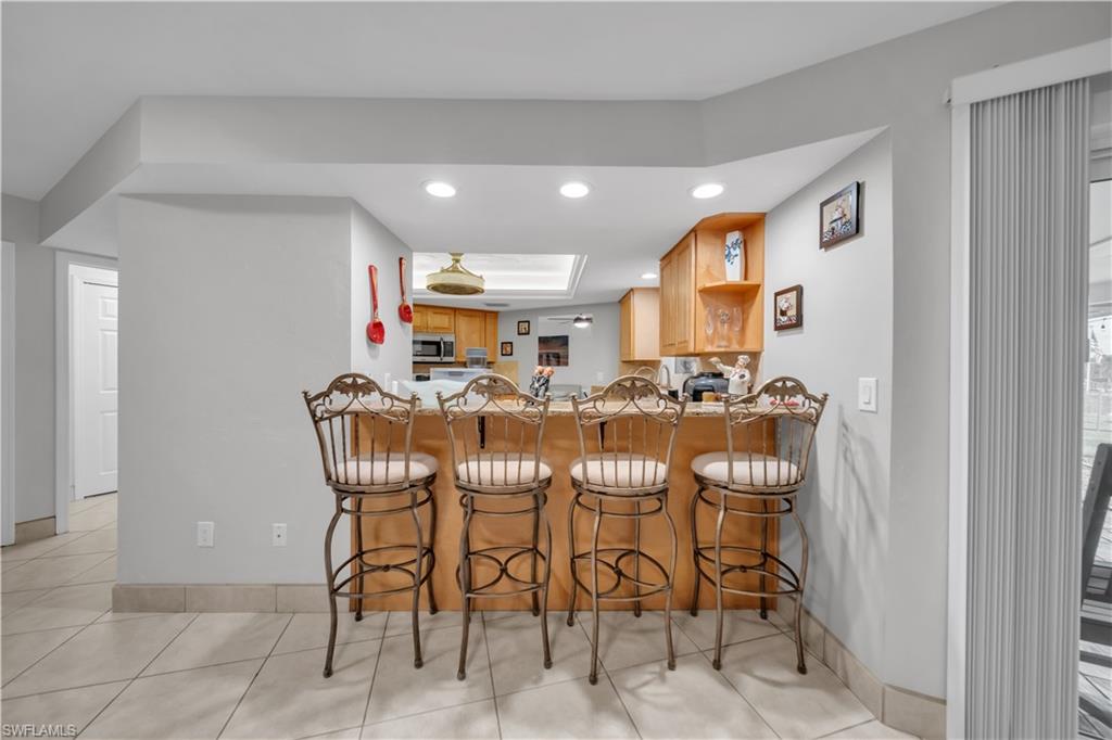 Kitchen with a breakfast bar area, recessed lighting, a peninsula, open shelves, and light tile patterned floors