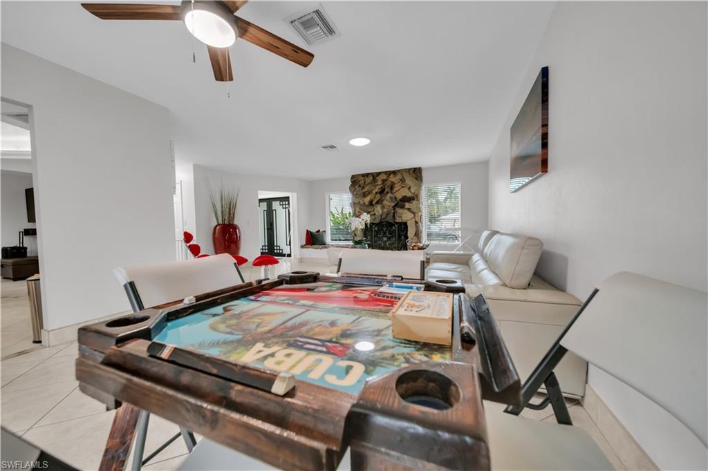 Dining space featuring a fireplace, light tile patterned flooring, and ceiling fan