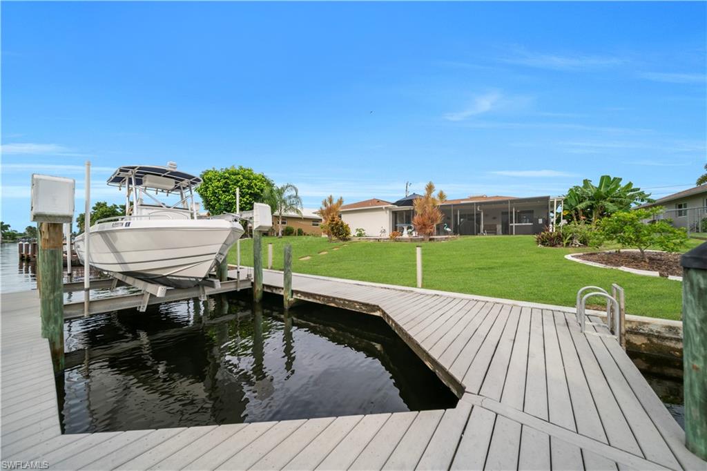Dock with boat lift, a yard, and a water view
