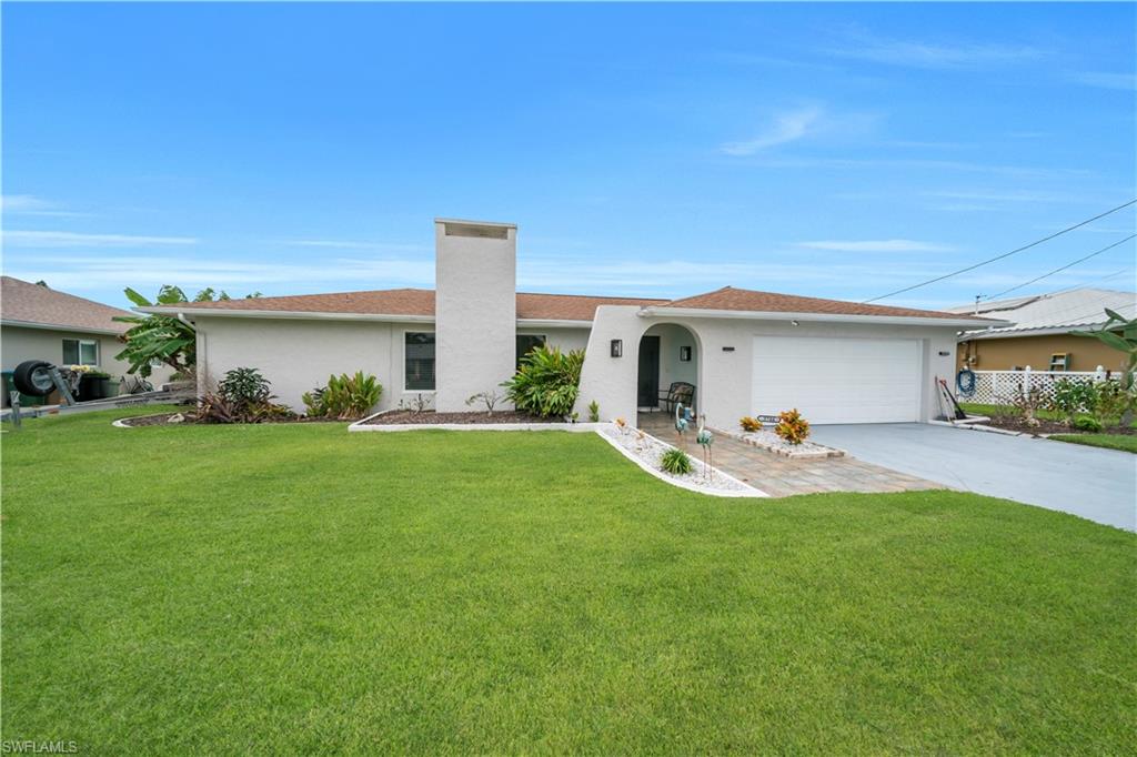 Single story home featuring stucco siding, a front lawn, concrete driveway, and a chimney
