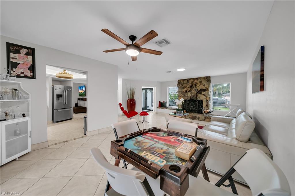 Dining area with light tile patterned floors, a ceiling fan, and a fireplace