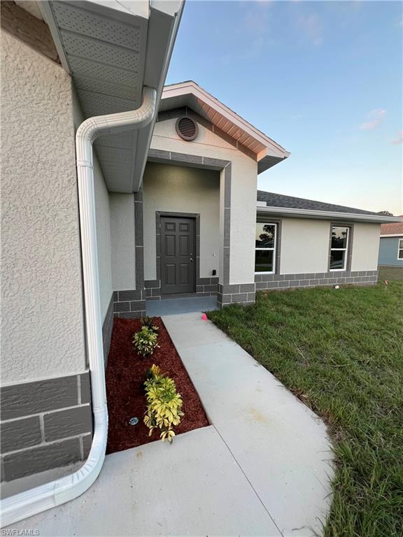 View of front of property featuring stucco siding, a front lawn, driveway, and an attached garage