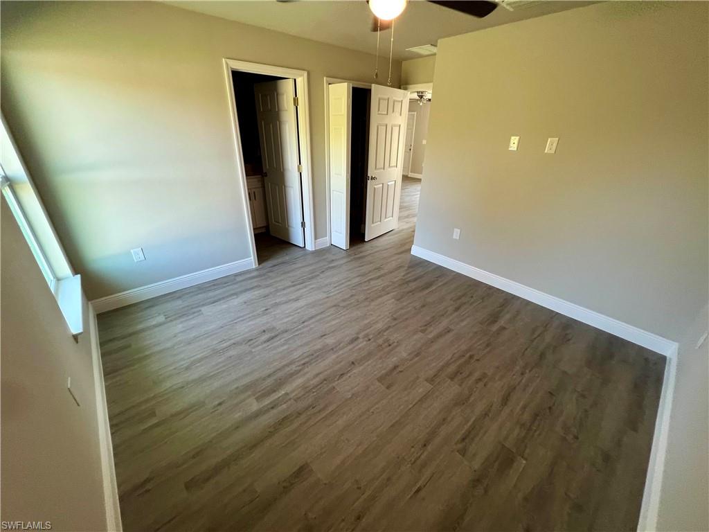 Kitchen featuring white cabinets, hanging light fixtures, light stone counters, light wood-style flooring, and a peninsula