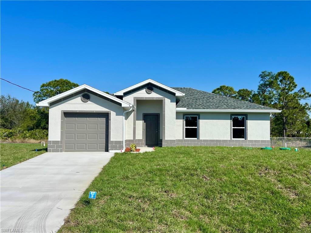 View of front of house featuring a front yard, concrete driveway, stucco siding, and an attached garage