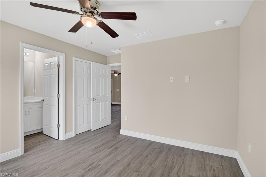 Unfurnished bedroom featuring light wood-type flooring, a ceiling fan, ensuite bathroom, and a closet