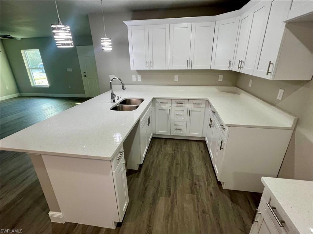 Kitchen with a peninsula, decorative light fixtures, light stone countertops, and white cabinets