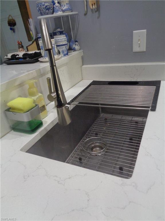 Kitchen view of light stone counters and a sink