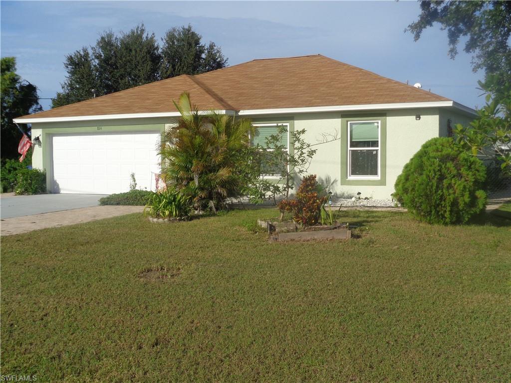 Ranch-style home with a front lawn, stucco siding, driveway, an attached garage, and roof with shingles